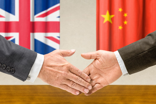 handshake in front of British and Chinese flags