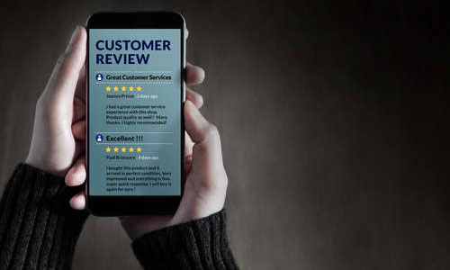 Hands holding a phone containing online reviews 