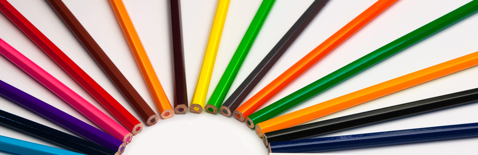 Coloured pencils lying in a rainbow shape