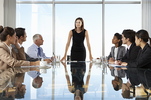 Chairwoman speaking to a boardroom of executives.