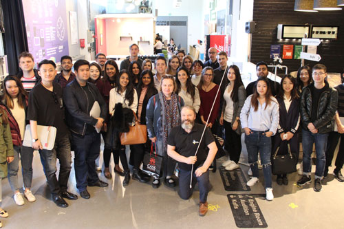 A large group of students pose for a photograph inside the Aalto Business School lobby.