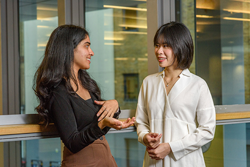 Female students (one South Asian, one East Asian) talking together on campus