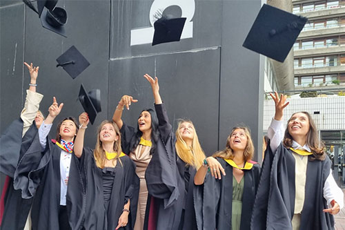 Student Lila Vialat throws her mortarboard in the air as she celebrates her graduation with friends at the Barbican Centre in July 2023