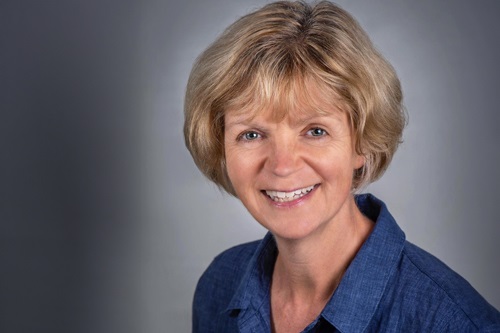 Headshot image of Angela Tennent on grey background. 