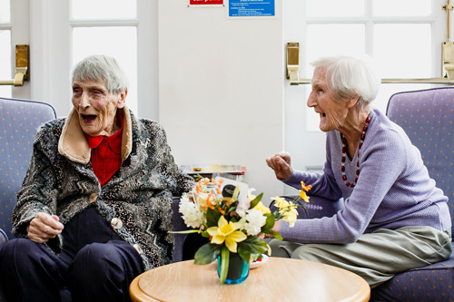Two elderly ladies (Joyce Webb and Beryl Fox) laughing together at Whiteley Village.