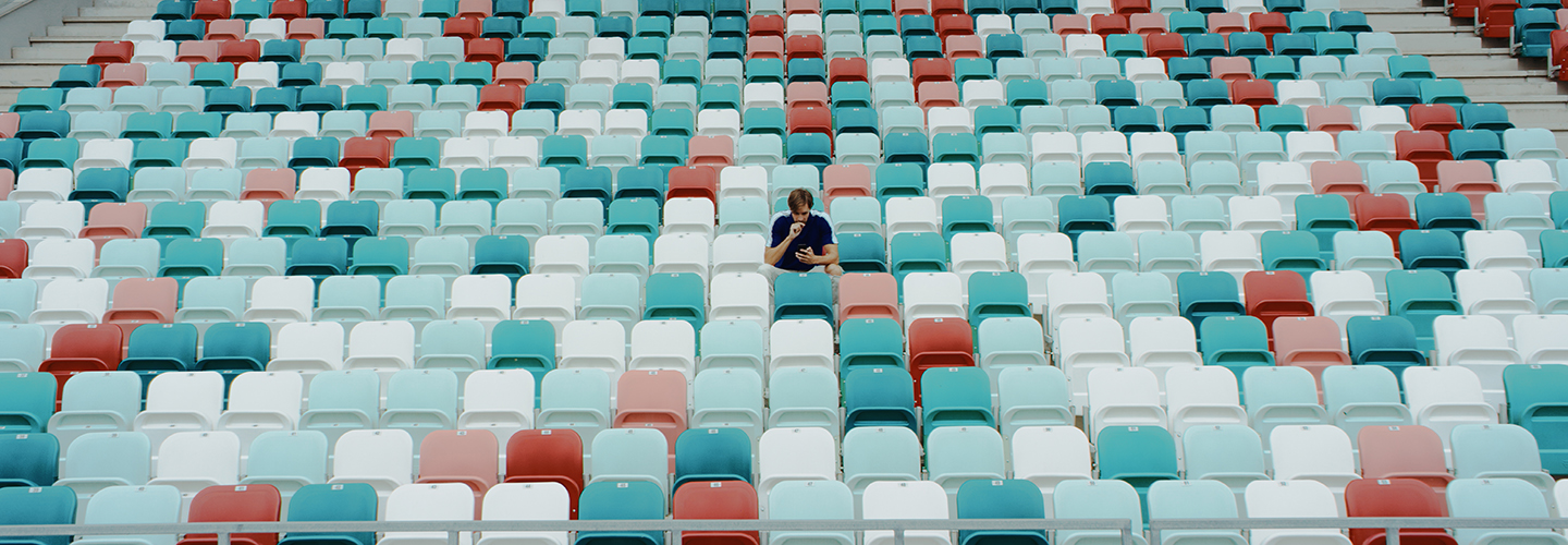 A single fan sits in an empty stadium