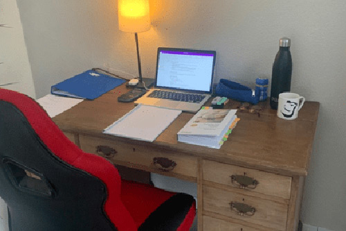 om England study at home space, a macbook, notepad and stationary on a wooden desk.