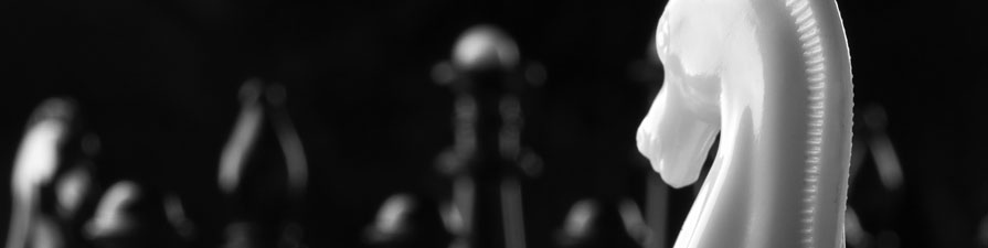 A white rook chess piece faces across the board to a row of opposing black pieces.