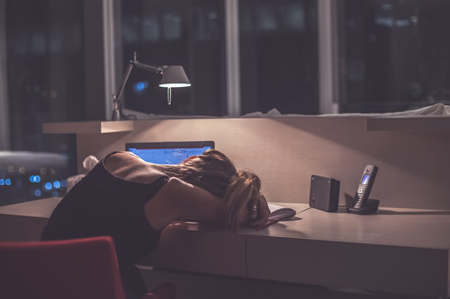 Female worker slumped, exhausted, at her desk
