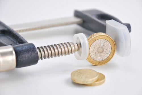 A pound coin is squeezed between a clamp