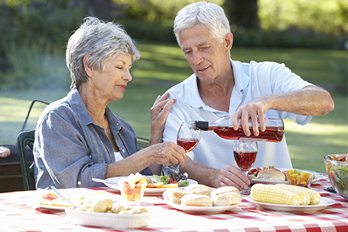 Senior couple enjoying a barbecue in the garden with wine