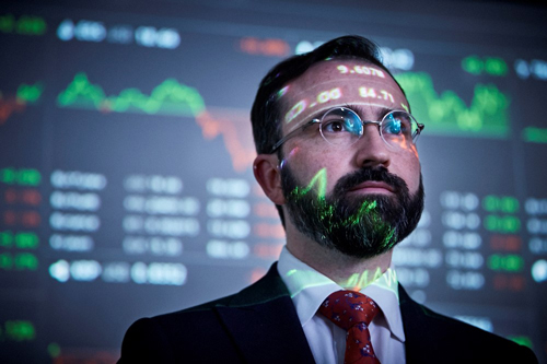 Man with stock market figures reflecting on his face